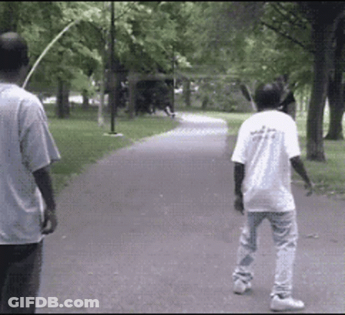 Two Men Walking In Park One Wearing White Shirt Saying A GIF