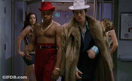 Two Men Walking, One In Fur Coat GIF