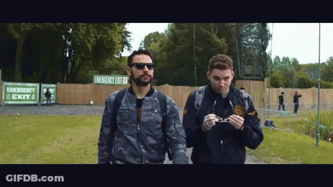 Two Men Walking Past Emergency Exit Sign GIF