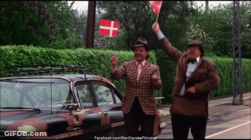 Two Men Waving Flags In Front Of A Camouflage Car With Facebook.com On The Bottom Right GIF