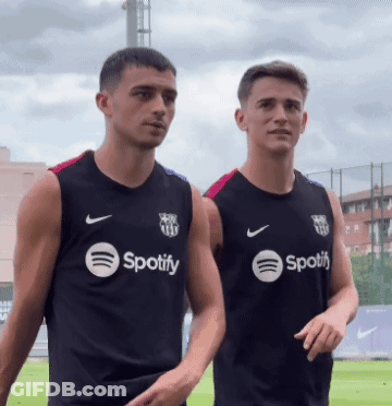 Two Men Wearing Black Spotify Shirts Stand Next To Each Other GIF