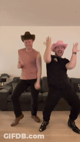 Two Men Wearing Cowboy Hats Are Dancing In Front Of A Couch GIF
