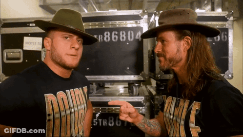 Two Men Wearing Cowboy Hats Are Standing Next To Each Other With One Wearing A Shirt That Says ' Down ' On It GIF
