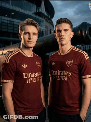 Two Men Wearing Emirates Fly Better Shirts Pose For A Picture GIF