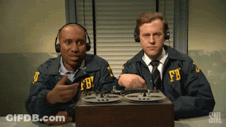 Two Men Wearing Fbi Uniforms Are Sitting At A Desk GIF