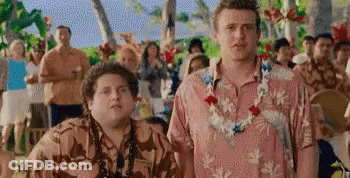 Two Men Wearing Hawaiian Shirts And Lei Are Standing Next To Each Other In Front Of A Crowd Of People . GIF