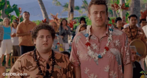 Two Men Wearing Hawaiian Shirts And Lei Are Standing Next To Each Other In Front Of A Crowd Of People . GIF