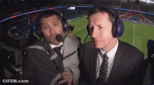 Two Men Wearing Headphones Are Talking To Each Other In A Stadium . GIF