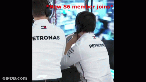 Two Men Wearing Petronas Shirts Are Looking At Something GIF