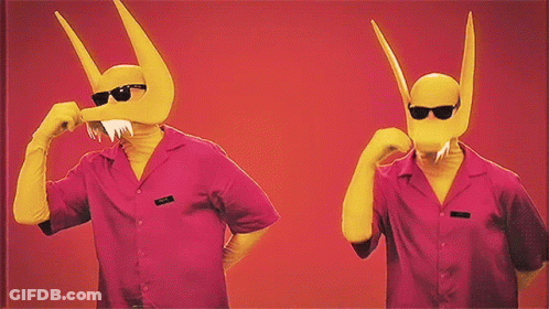 Two Men Wearing Pink Shirts And Yellow Masks With Horns Are Standing Next To Each Other On A Red Background GIF