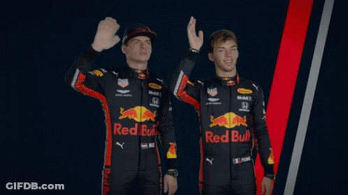Two Men Wearing Red Bull Racing Uniforms Are Waving GIF