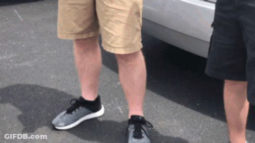 Two Men Wearing Shorts And Sneakers Are Standing Next To Each Other In Front Of A Car GIF