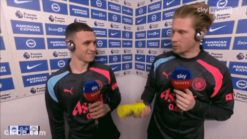 Two Men Wearing Sky Sports Shirts Are Talking To Each Other GIF