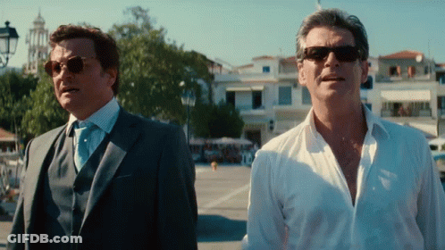 Two Men Wearing Suits And Sunglasses Are Standing Next To Each Other GIF