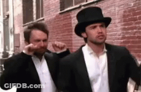 Two Men Wearing Suits And Top Hats Are Standing Next To Each Other . GIF