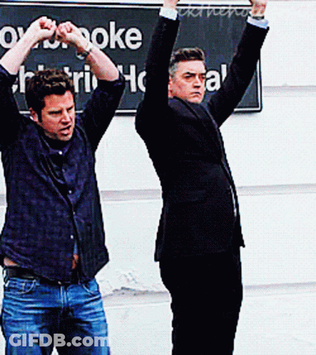 Two Men With Arms Up At Karaoke GIF