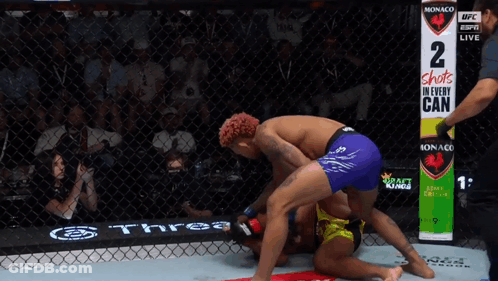 Two Men Wrestling In Ring With Sign 2 Shots In Every Can GIF