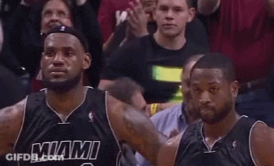 Two Miami Heat Basketball Players Are Standing Next To Each Other In Front Of A Crowd During A Game . GIF