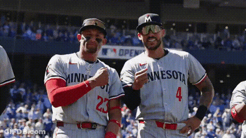Two Minnesota Baseball Players Are Posing For A Picture On The Field GIF