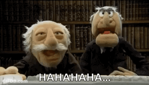 Two Muppets Are Laughing In Front Of A Bookshelf While Sitting At A Desk . GIF
