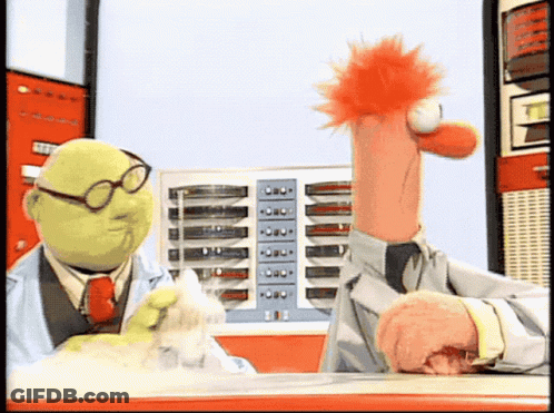 Two Muppets Are Sitting At A Table And One Is Wearing Glasses And A Lab Coat GIF