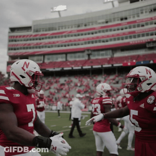 Two Nebraska Football Players Shake Hands In Front Of Stadium GIF