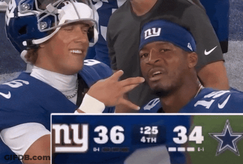 Two New York Giants Players Standing Next To Scoreboard GIF