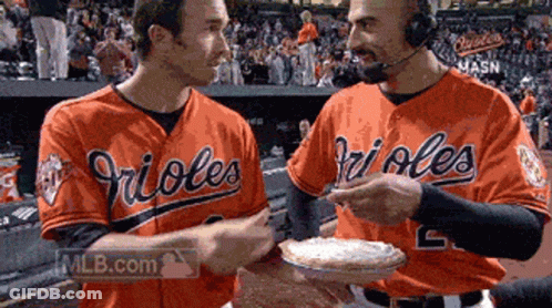 Two Orioles Baseball Players Holding A Pie GIF