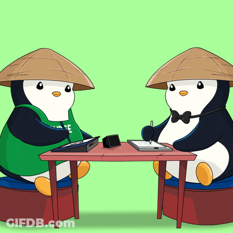 Two Penguins Sitting At Table One Wearing Green Shirt Saying Ice GIF
