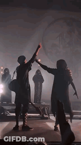 Two People Are Dancing On A Stage In A Dark Room . GIF