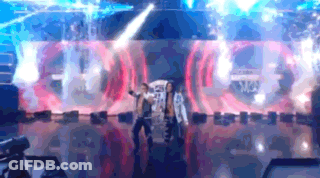 Two People Are Dancing On A Stage In Front Of A Large Screen That Says ' A ' On It . GIF
