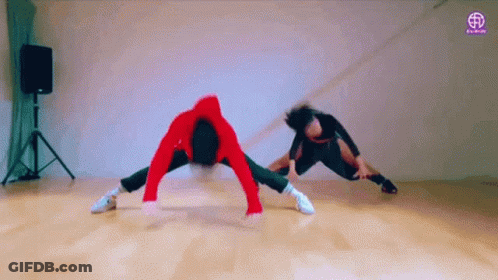 Two People Are Doing A Handstand On A Wooden Floor In A Dance Studio . GIF