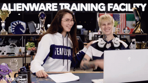 Two People Are Sitting In Front Of A Laptop With The Words Alienware Training Facility Written Above Them GIF