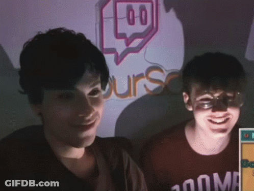 Two People Are Smiling In Front Of A Sign That Says Urs GIF