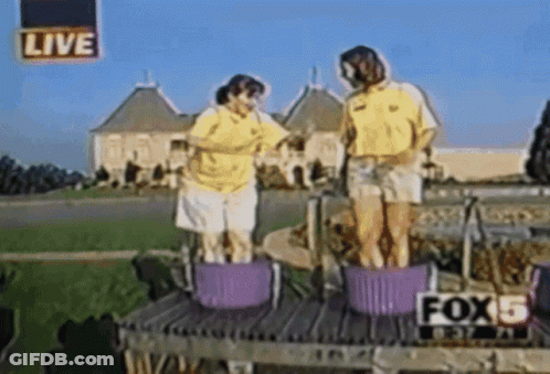 Two People Are Standing In Buckets In Front Of A Live Sign That Says Fox 5 GIF