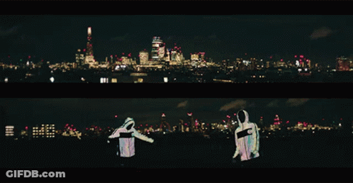 Two People Are Standing In Front Of A City At Night GIF