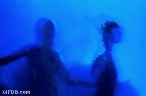 Two People Are Standing In Front Of A Lightning Bolt In A Dark Room . GIF