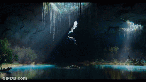 Two People Are Swimming In A Cave With A Light Shining Through The Trees GIF