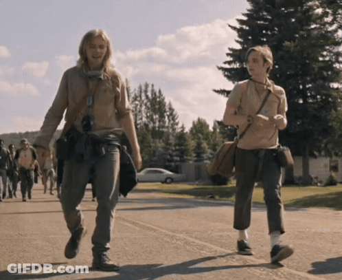 Two People Are Walking Down A Street And One Has A Purse Around Her Shoulder GIF