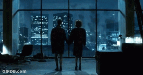 Two People At Window Overlooking City At Night GIF
