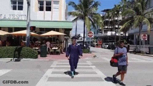 Two People Crossing Street In Front Of Majesty Restaurant GIF