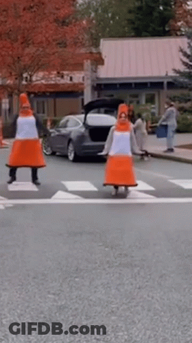 Two People Dressed As Traffic Cones Crossing Street GIF