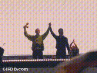Two People High-Fiving On Stage In Front Of Crowd GIF