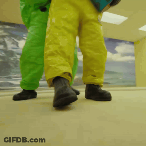Two People In Green And Yellow Suits Walking GIF