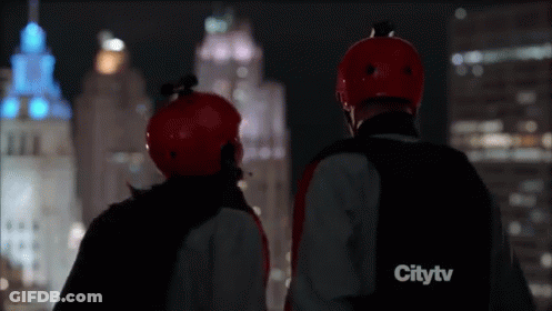 Two People In Red Helmets Watching City At Night GIF