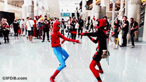 Two People In Spiderman And Deadpool Costumes Are Dancing In Front Of A Crowd GIF