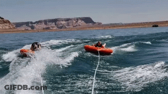 Two People In Tubes Are Being Pulled By A Boat GIF