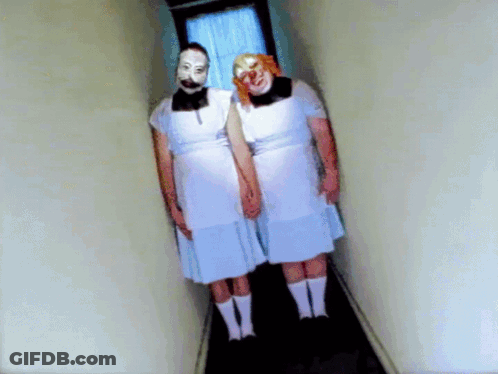 Two People In White Dresses And Clown Masks Holding Hands In Hallway GIF