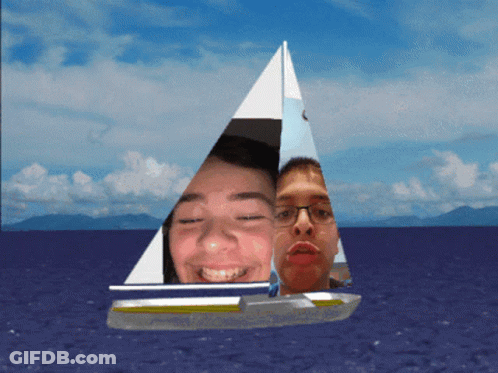 Two People On Sailboat In Ocean With Mountains GIF