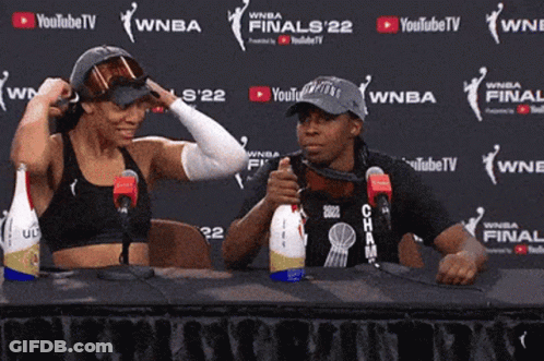 Two People Sitting At A Table In Front Of A Wall That Says Youtubetv GIF